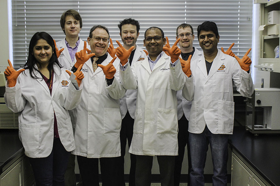Faculty and students giving Go Pokes sign